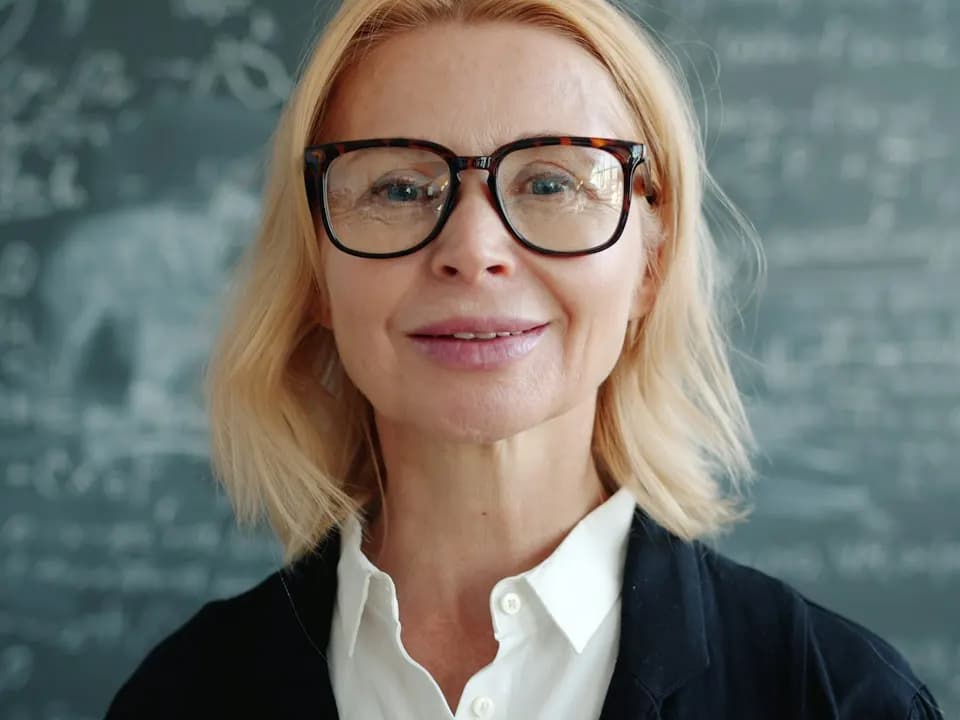 Porträt einer Frau mit Brille vor einer Tafel