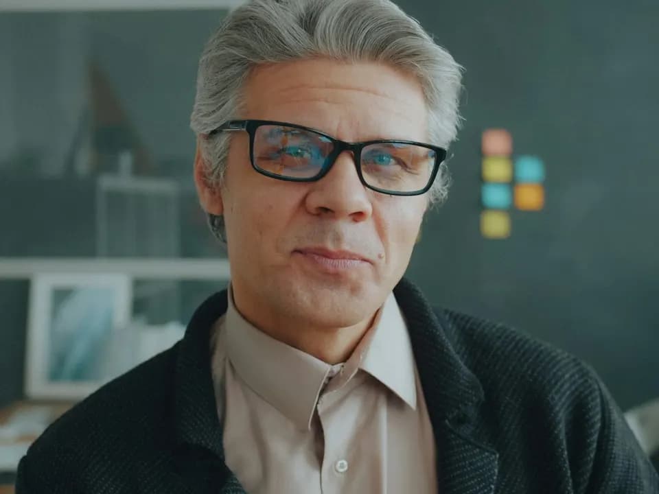 Porträt eines grauhaarigen Mannes mit Brille in einem Büro